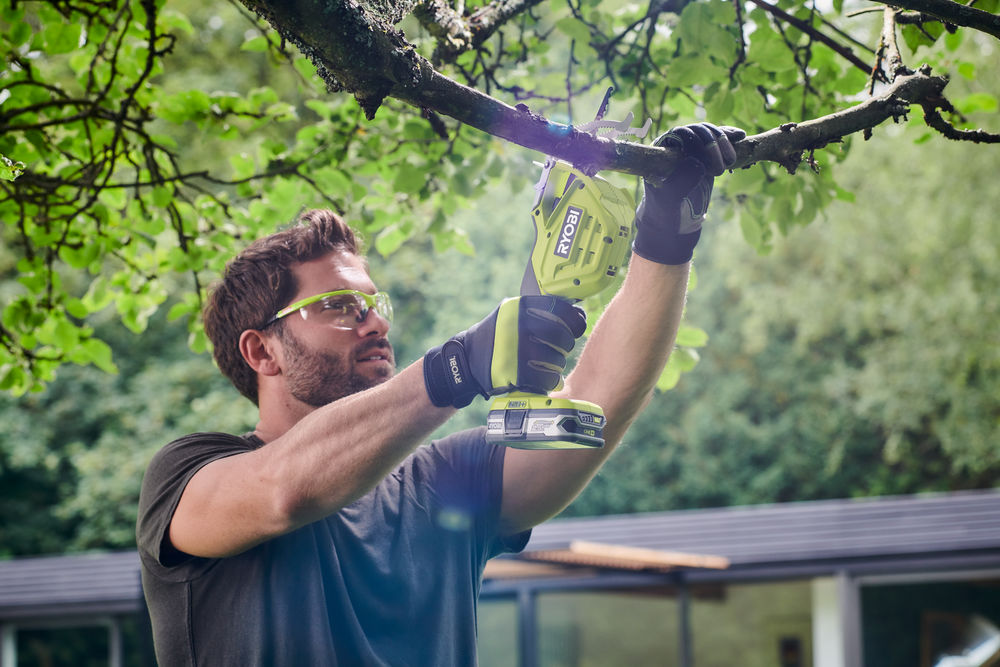 Mężczyzna przycina drzewo za pomocą pilarki szablastej na akumulator RYOBI